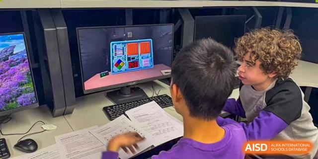 A student from Tsinghua International School Daoxiang Lake working on a computer at a desk in a classroom or lab.