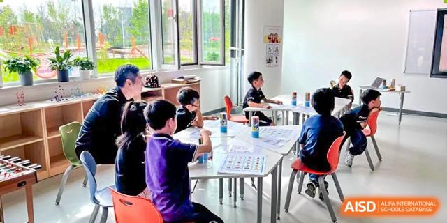 Students from Tsinghua International School Daoxiang Lake sitting at tables and working or discussing in a classroom.