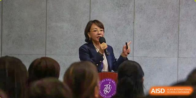 A female speaker giving a presentation to an audience in a classroom or conference setting at Tsinghua International School Daoxiang Lake.