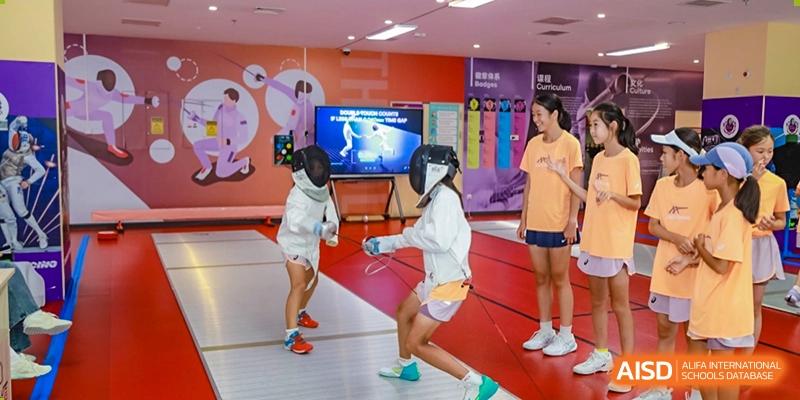 Two students wearing protective gear and fencing in an indoor sports area at Tsinghua International School Daoxiang Lake.