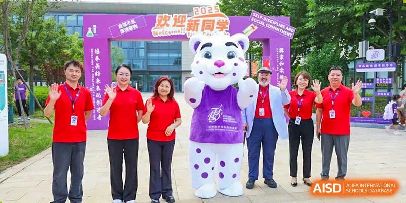 A school mascot and two adults in front of a "Welcome" banner at Tsinghua International School Daoxiang Lake during a social event or orientation.