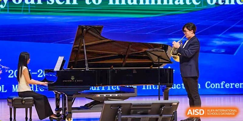 A concert grand piano on a stage under spotlights during a performance at Tsinghua International School Daoxiang Lake.