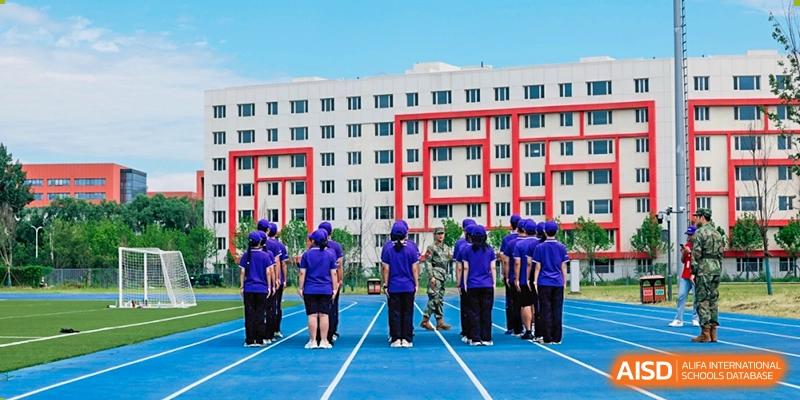Students from Tsinghua International School Daoxiang Lake performing a synchronized activity in front of a red and white residence building.