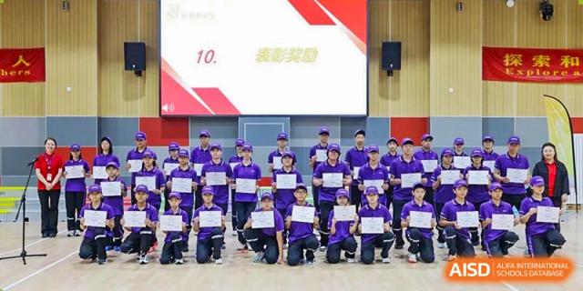 A group of students from Tsinghua International School Daoxiang Lake posing on stage with awards after a competition.