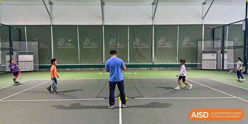 A person in blue attire cleaning or maintaining an outdoor tennis court at Tsinghua International School Daoxiang Lake.