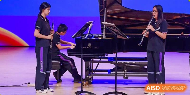 A student from Tsinghua International School Daoxiang Lake performing on a grand piano on a stage.