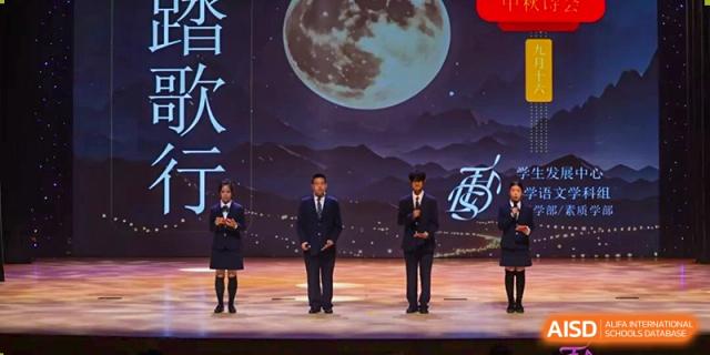 Two men shaking hands on a stage with a dramatic full moon backdrop at Tsinghua International School Daoxiang Lake.