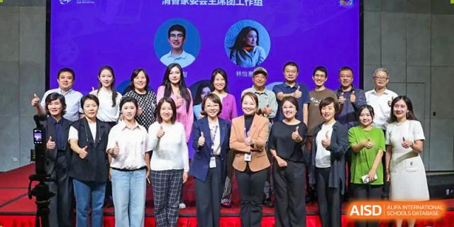 A group of adults and staff members from Tsinghua International School Daoxiang Lake posing together indoors.