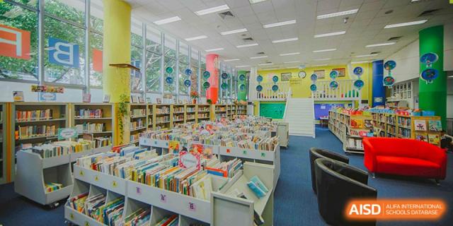 A wide view of the well-stocked, colorful library at American International School of Guangzhou (AISG), filled with bookshelves and ample natural light.