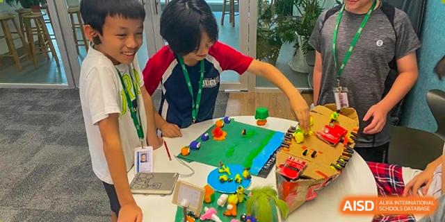 Students at American International School of Guangzhou (AISG) work together on a hands-on learning activity using colorful building blocks on a table.