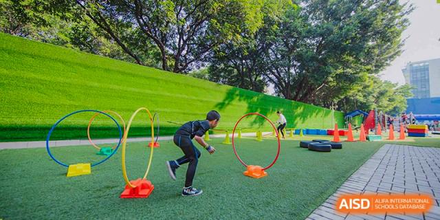 A student engages in agility training with cones and a hoop on the outdoor turf field at the American International School of Guangzhou (AISG).