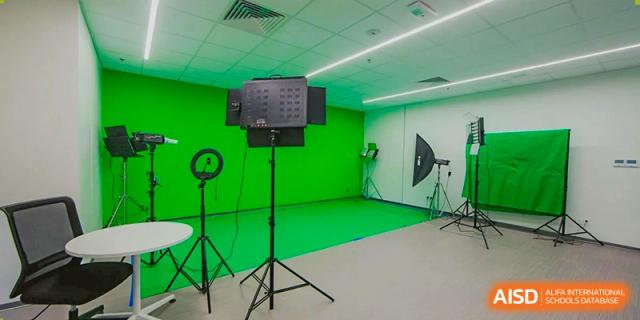 A fully equipped green screen studio with camera lights and professional rigging for video production at the American International School of Guangzhou (AISG).