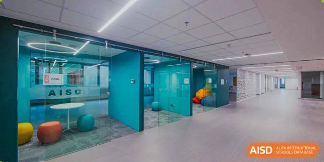 A contemporary and bright interior space with teal glass walls and modern collaborative furniture at the American International School of Guangzhou (AISG).