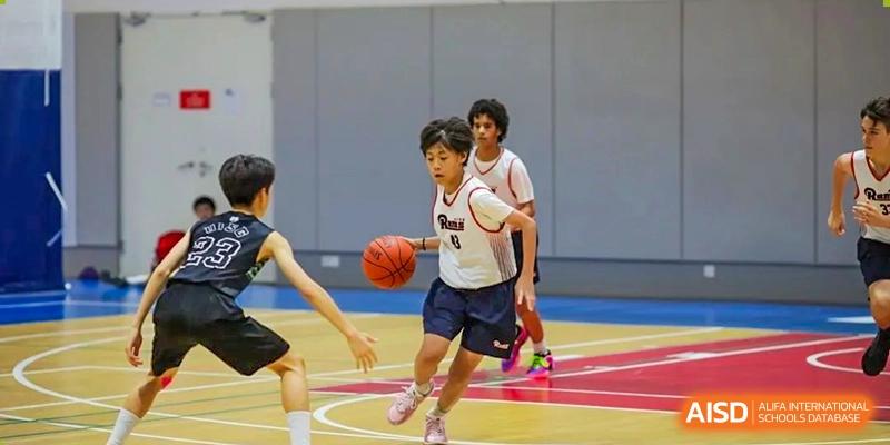 Male students playing basketball on an outdoor court during a game or practice session at the American International School of Guangzhou (AISG).