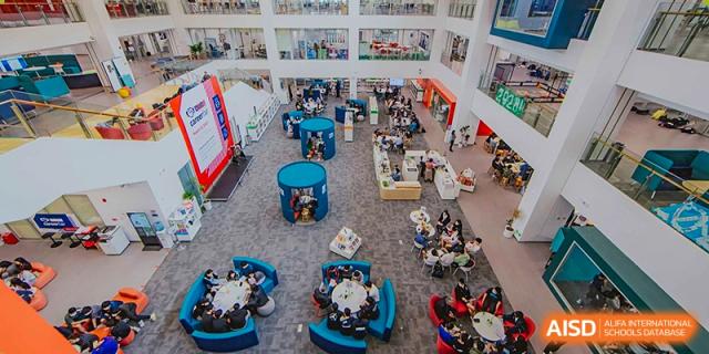 An overhead view of the multi-level school library/learning commons with groups of students seated in blue modular furniture at the American International School of Guangzhou (AISG).