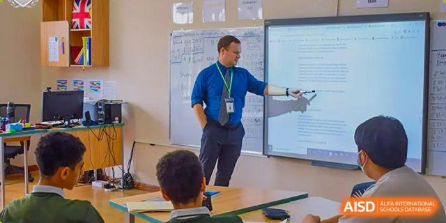 A male teacher pointing at a lesson displayed on an interactive whiteboard in a classroom full of students at Britannia International School Guangzhou.