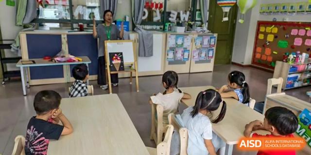 Young students seated at small tables in a bright classroom or activity room at Britannia International School Guangzhou.