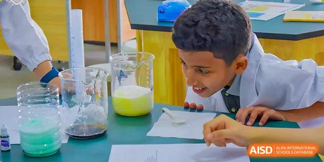A student observing a chemical reaction in a beaker during a science experiment at Britannia International School Guangzhou.