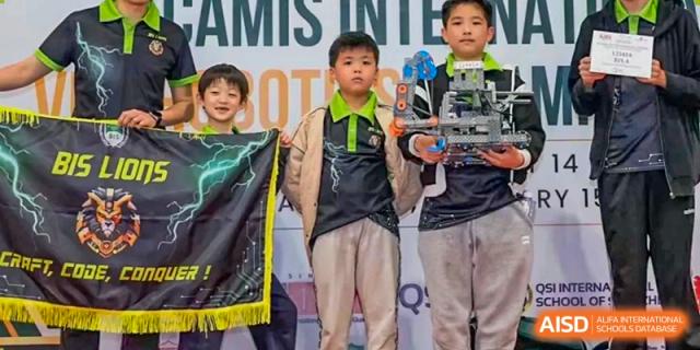 Two students holding a banner and a trophy after a robotics or competition event at Britannia International School Guangzhou.