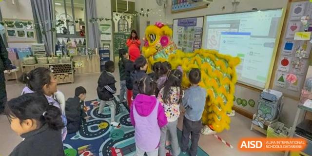 Students gathered around a large yellow inflatable dragon in a classroom for a cultural celebration at Britannia International School Guangzhou.