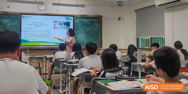 A teacher interacting with students in a classroom setting at the Affiliated School of JNU for Hong Kong & Macao Students.