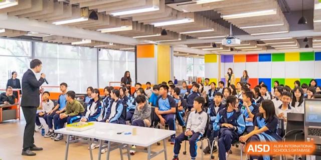 A large group of students from the Affiliated School of JNU for Hong Kong & Macao Students attentively seated for a lecture or assembly in an open area.