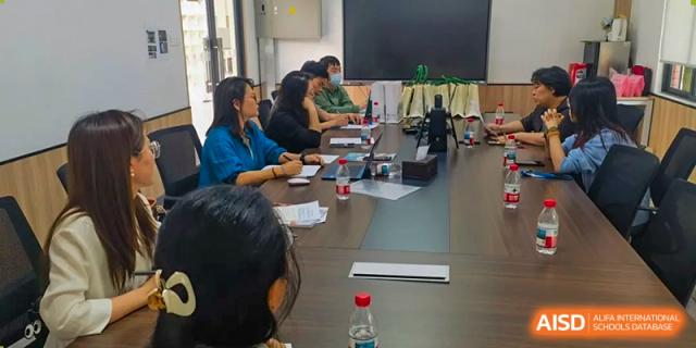 Teachers or administrators from the Affiliated School of JNU for Hong Kong & Macao Students participating in a meeting around a conference table.