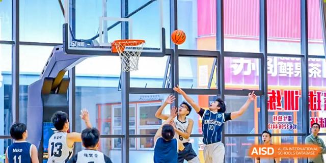 Students from the Affiliated School of JNU for Hong Kong & Macao Students practicing shooting on a bright, modern indoor basketball court.