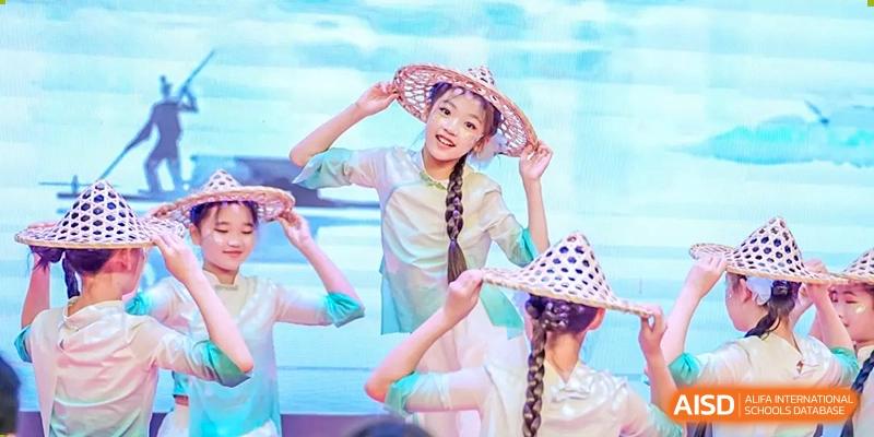 Students from the Affiliated School of JNU for Hong Kong & Macao Students performing a traditional dance while wearing straw hats.