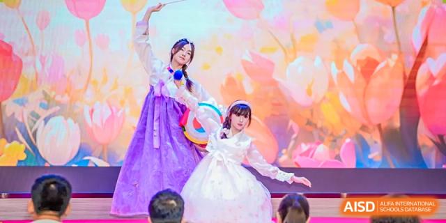 Students from the Affiliated School of JNU for Hong Kong & Macao Students performing a colorful traditional or folk dance on stage.