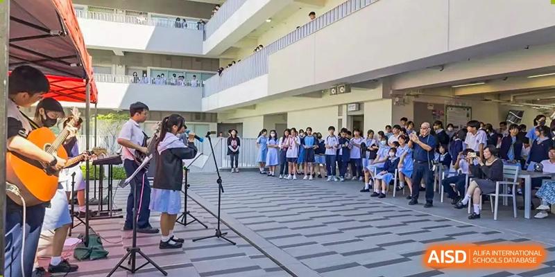 Students from the Affiliated School of JNU for Hong Kong & Macao Students attending an outdoor event or assembly near the school building.