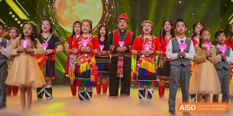A group of performers from the Affiliated School of JNU for Hong Kong & Macao Students in vibrant ethnic minority traditional costumes on stage.