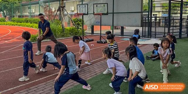 Students from the Affiliated School of JNU for Hong Kong & Macao Students practicing basketball drills on an outdoor court.