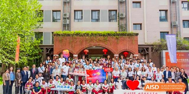 A large crowd of students and teachers gathered outside under an archway for a group photo during a celebratory event at Beijing Academy International Department (BAID).
