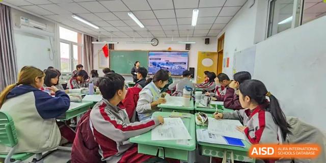 Students seated at green desks, working on assignments and collaborating during a class at Beijing Academy International Department (BAID).