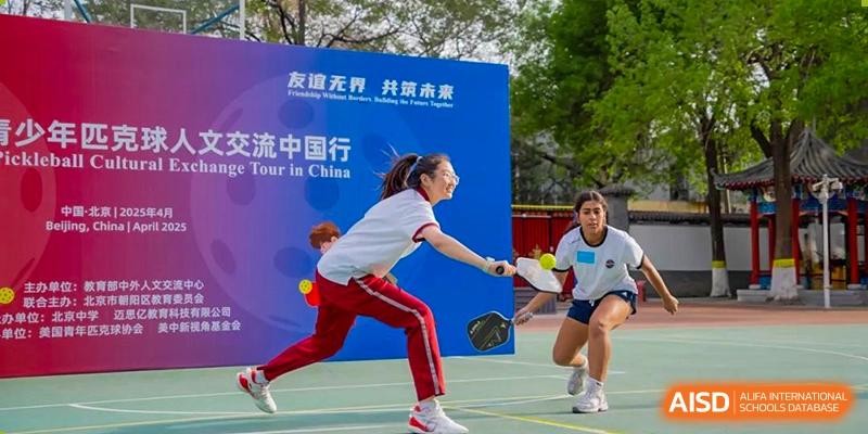 A female student in a red and white uniform playing an outdoor racquet sport during a tournament or competition at Beijing Academy International Department (BAID).