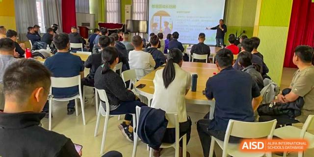 Students attentively facing the front of a classroom during a lecture or presentation, with some taking notes, at Beijing SMIC Private School.