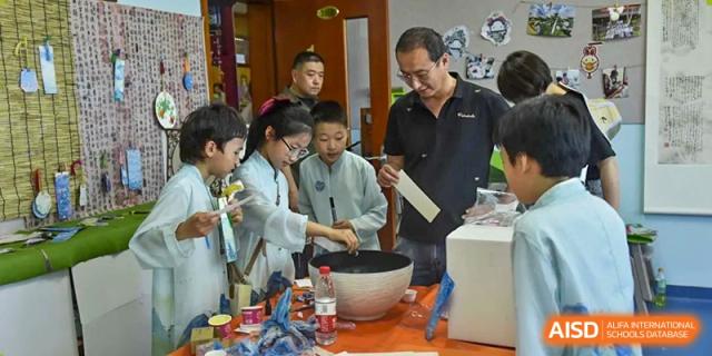 A male teacher guiding students through a hands-on experiment, involving mixing ingredients in a large bowl on a table, at Beijing SMIC Private School.
