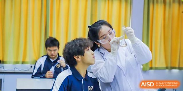A teacher or medical professional examining a male student's ear using a specialized instrument in a classroom at Boya International Academy (BIA).