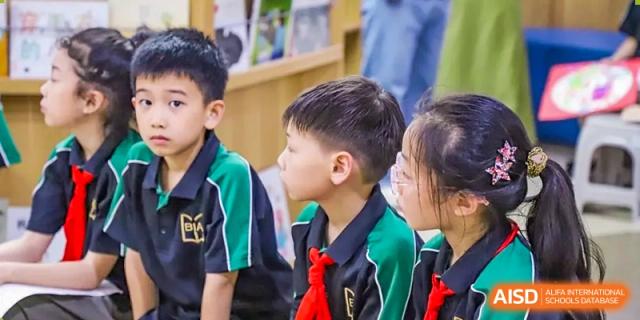 A close-up of young students from Boya International Academy (BIA) in green and black uniforms attentively listening to a lesson or presentation.