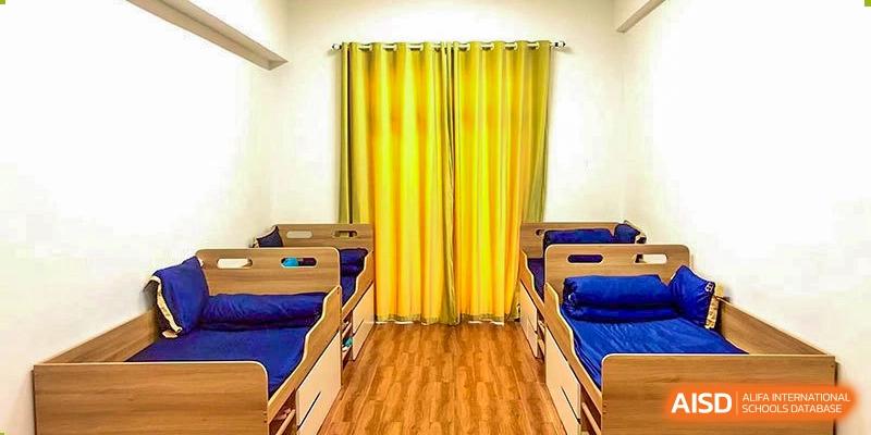 A napping or rest room at Boya International Academy (BIA) with small cots/beds lined up and bright yellow curtains.