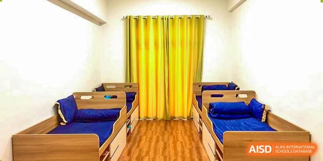 A napping or rest room at Boya International Academy (BIA) with small cots/beds lined up and bright yellow curtains.