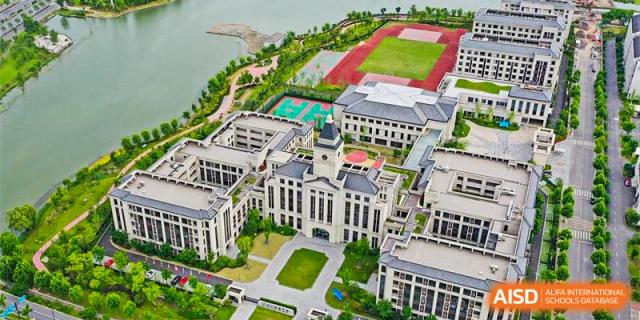 An aerial view of the beautiful campus of Boya International Academy (BIA), showing large modern buildings, sports fields, and extensive greenery.
