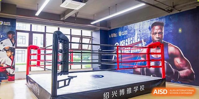 An interior view of a fitness facility or training room at Boya International Academy (BIA) featuring a full-sized boxing ring.