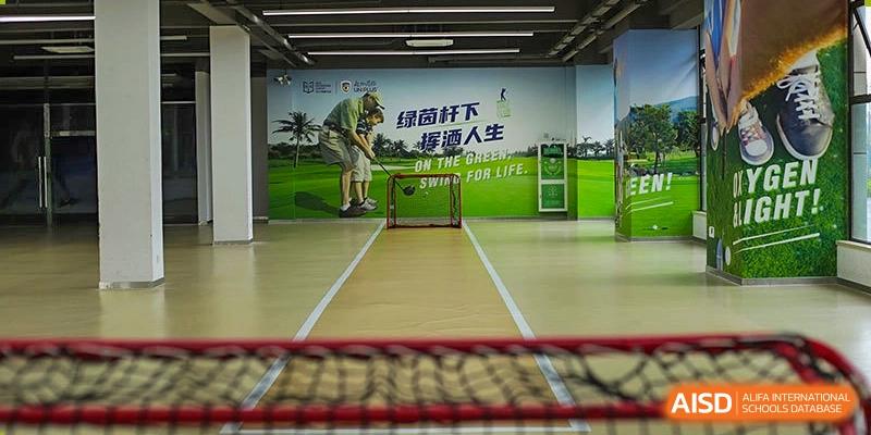 An indoor sports area at Boya International Academy (BIA) set up for cricket or golf practice, featuring a net and a large wall graphic.