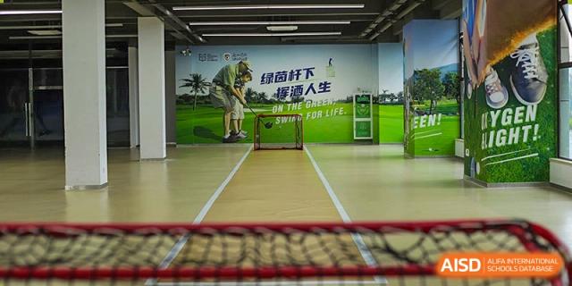 An indoor sports area at Boya International Academy (BIA) set up for cricket or golf practice, featuring a net and a large wall graphic.