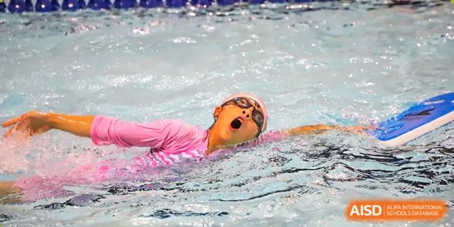 A student from Boya International Academy (BIA) wearing goggles and a swim cap, swimming laps in the school's pool.