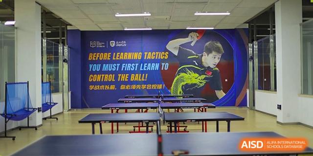 An indoor sports room at Boya International Academy (BIA) dedicated to table tennis, featuring a large motivational poster.