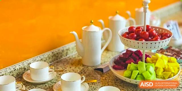 A close-up of a breakfast or tea display at Boya International Academy (BIA), showing white teapots, cups, and fresh fruit.