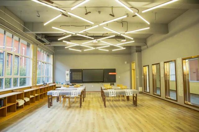 A bright, modern classroom or multi-purpose room featuring stylish ceiling lights and light wood floors, Brilliant Light School SJZ.